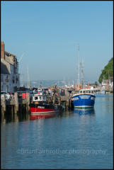 Boats moored alongside Custom House Quay in Weymouth Harbour, Dorset.